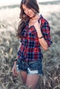 Beautiful girl field. Summer nature. Corrects long hair. In a shirt and shorts. A sunny day woman brunette, close-up Royalty Free Stock Photo