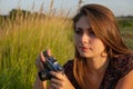 Beautiful girl with a film camera in her hands makes a photo in the meadow while traveling Royalty Free Stock Photo