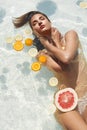 Beautiful Girl Floating With Citrus. Woman In Bikini Swimming In Pool At Tropical SPA Resort. Royalty Free Stock Photo