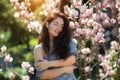 Beautiful girl with flowers of magnolia. Portrait of young smiling brunette woman under blossom magnolia tree. Royalty Free Stock Photo