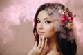 Beautiful girl with flowers. Spring woman. Lady with bright makeup and a flowering branch in her hair. Spring time. On a pink Royalty Free Stock Photo