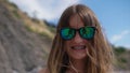 The beautiful girl in sunglasses with reflection of the cameramen on the beach