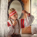 A beautiful girl in a folk costume looks at the Rowan berry beads