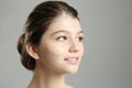 Beautiful girl with foundation smear on her face against grey background Royalty Free Stock Photo
