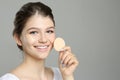 Beautiful girl with foundation smear on her face holding sponge against grey background. Space for text Royalty Free Stock Photo