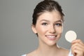 Beautiful girl with foundation smear on her face holding sponge against grey background Royalty Free Stock Photo