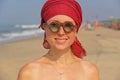 Beautiful girl freak with a red armband on her head, on the background of the sea. Summer girl in round wooden glasses. Unusual