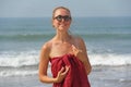 Beautiful girl freak in a red dress and blond hair, on the background of the sea. Summer girl in round wooden glasses. Unusual Royalty Free Stock Photo