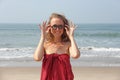 Beautiful girl freak in a red dress and blond hair, on the background of the sea. Summer girl in round wooden glasses. Unusual Royalty Free Stock Photo