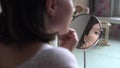 Beautiful girl in front of a mirror with a cotton pad smears foundation