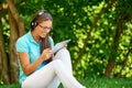 Beautiful girl with gadget listening to the music in summer park