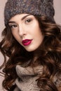 Beautiful girl with gentle makeup, curls in brown knit hat. Warm winter image. Beauty face. Royalty Free Stock Photo