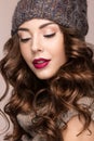 Beautiful girl with gentle makeup, curls in brown knit hat. Warm winter image. Beauty face. Royalty Free Stock Photo