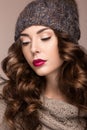 Beautiful girl with gentle makeup, curls in brown knit hat. Warm winter image. Beauty face. Royalty Free Stock Photo