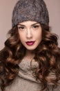 Beautiful girl with gentle makeup, curls in brown knit hat. Warm winter image. Beauty face. Royalty Free Stock Photo
