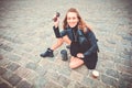 Beautiful girl in glam rock style wear sitting on a paving stones and drinking street coffee. Feeling of freedom Royalty Free Stock Photo