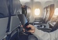 Beautiful girl in glasses and hat with backpack holding phone in the aircraft. Traveler in the airplain. Young asian woman travele