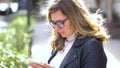 A beautiful girl with glasses standing on the stree with smartphone, smiling and work with it. Beauty people