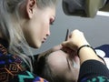 Beautiful girl glues eyelashes to client in studio. Royalty Free Stock Photo