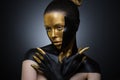Beautiful girl with gold and black paint on her face and body. Female portrait with creative makeup.way