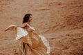 A beautiful girl in a golden with brilliant dress with wings, suit is dancing an oriental, East dance in the desert Royalty Free Stock Photo