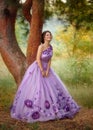 Beautiful girl in a gorgeous purple dress standing under a tree Royalty Free Stock Photo