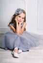 Beautiful girl in gray dress and pointe shoes is posing on the floor in the room Royalty Free Stock Photo