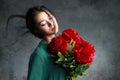 Beautiful girl in the green dress with flowers peonies in hands on a light gray background. Joyful Asian female model posing in Royalty Free Stock Photo