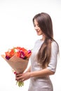 Beautiful girl in the grey dress with flowers tulips in hands on a white background Royalty Free Stock Photo