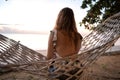 Beautiful girl in a hammock looks at the sunset by the sea Royalty Free Stock Photo