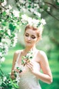 Beautiful girl hands with a branch of a blossoming apple tree. Young beautiful blonde woman in blooming garden. Royalty Free Stock Photo