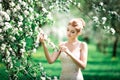 Beautiful girl hands with a branch of a blossoming apple tree. Young beautiful blonde woman in blooming garden. Royalty Free Stock Photo