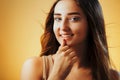 Beautiful girl with hands near face on orange colored background, young woman portrait, concept of female beauty Royalty Free Stock Photo