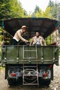 A beautiful girl and a handsome man in military truck. Lovestory. Military vehicle. Military fashion.Carpathian mountains