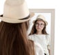 Beautiful girl in hat looks in mirror, Studio portrait on white background