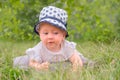 Beautiful girl in hat, panama having fun outdoor. Toddler lying in the grass. Royalty Free Stock Photo