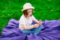 A beautiful girl in a hat, playing with a toy to drink on the green grass.in the park, on a summer day