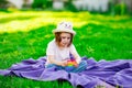 A beautiful girl in a hat, playing with a toy to drink on the green grass.in the park, on a summer day