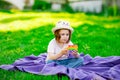 A beautiful girl in a hat, playing with a toy to drink on the green grass.in the park, on a summer day