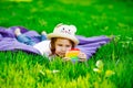 A beautiful girl in a hat, playing with a toy to drink on the green grass.in the park, on a summer day