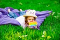 A beautiful girl in a hat, playing with a toy to drink on the green grass.in the park, on a summer day