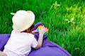 A beautiful girl in a hat, playing with a toy to drink on the green grass.in the park, on a summer day