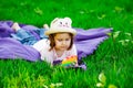 A beautiful girl in a hat, playing with a toy to drink on the green grass.in the park, on a summer day