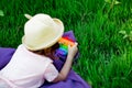 A beautiful girl in a hat, playing with a toy to drink on the green grass.in the park, on a summer day