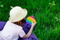 A beautiful girl in a hat, playing with a toy to drink on the green grass.in the park, on a summer day