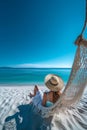 Beautiful girl in hat on sandy beach. Woman on seashore relaxing on swing on vacation