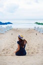 Beautiful girl in a hat sits with her back on a sandy beach Royalty Free Stock Photo