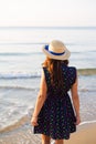 Beautiful girl in a hat stands with her back on a sandy beach. Royalty Free Stock Photo