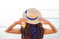 Beautiful girl in a hat stands with her back on a sandy beach Royalty Free Stock Photo