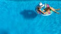 Beautiful girl in hat in swimming pool aerial top view from above, woman relaxes and swims on inflatable ring donut and has fun